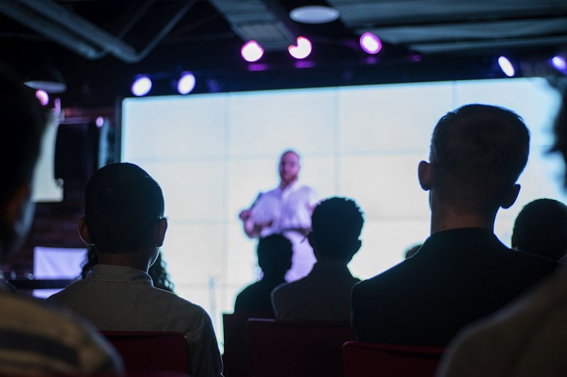 Audience watching a speaker on a large screen