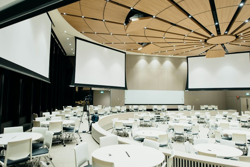 Empty event room with round tables and projection screens